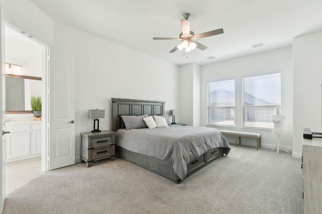 bedroom featuring ensuite bathroom, light carpet, and ceiling fan