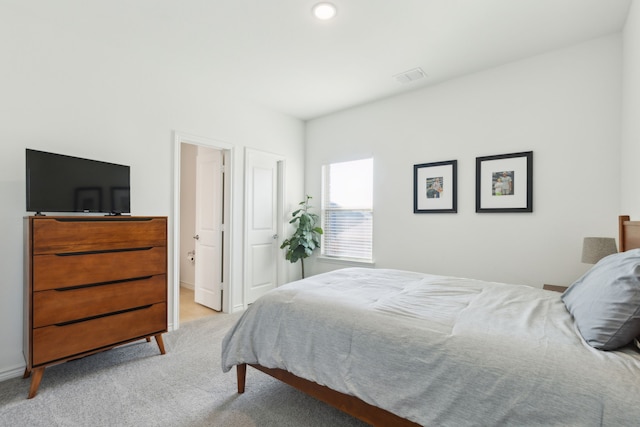 bedroom with light colored carpet and connected bathroom