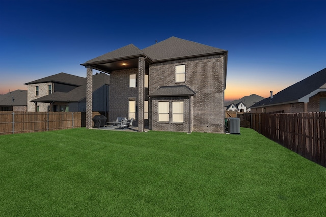 back house at dusk featuring central AC, a yard, and a patio area