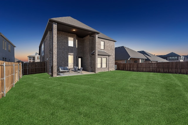 back house at dusk featuring a patio and a yard