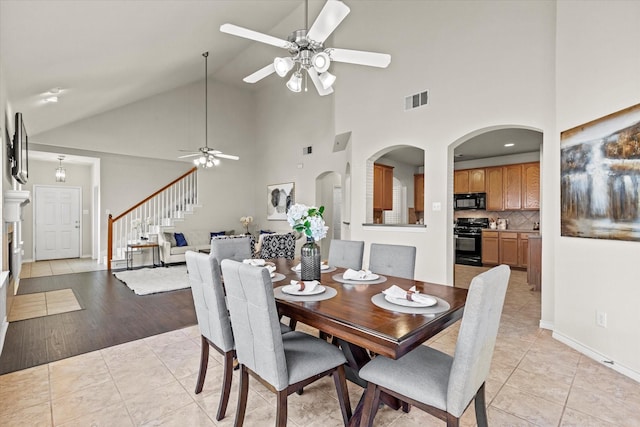 tiled dining space featuring high vaulted ceiling and ceiling fan