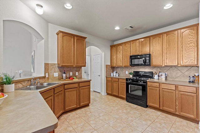 kitchen featuring tasteful backsplash, sink, light tile patterned floors, and black appliances