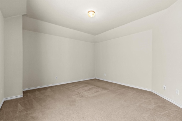 carpeted spare room with vaulted ceiling