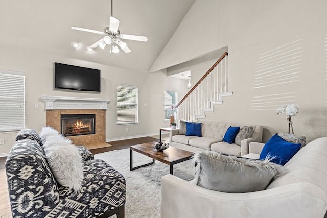 living room with a tiled fireplace, ceiling fan, hardwood / wood-style floors, and high vaulted ceiling