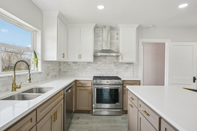 kitchen featuring white cabinets, a kitchen island, wall chimney range hood, and appliances with stainless steel finishes