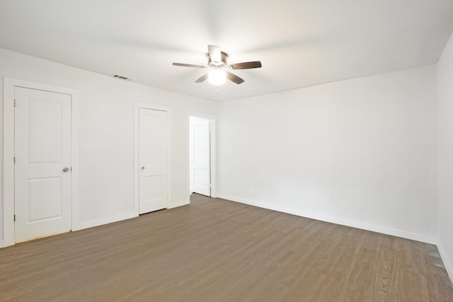 empty room with ceiling fan and dark hardwood / wood-style flooring