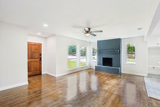 unfurnished living room featuring a fireplace, wood-type flooring, and ceiling fan