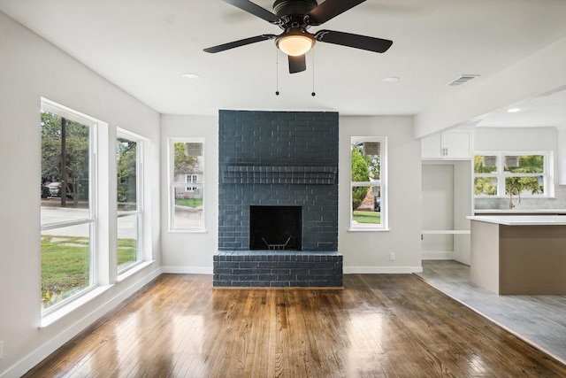 unfurnished living room with a brick fireplace, a healthy amount of sunlight, and hardwood / wood-style flooring