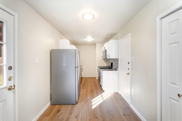 kitchen with decorative backsplash, white cabinets, stainless steel appliances, and light wood-type flooring