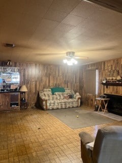 living room with ceiling fan and wood walls