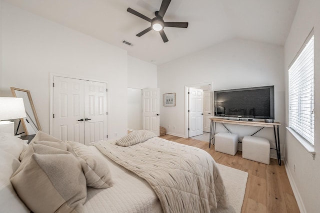 bedroom featuring a closet, light hardwood / wood-style floors, ceiling fan, and lofted ceiling