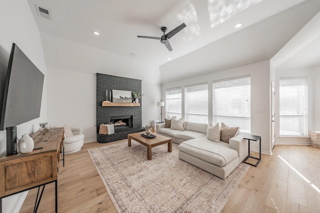 living room with ceiling fan, light wood-type flooring, and a brick fireplace