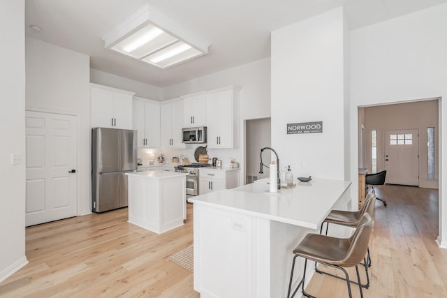 kitchen featuring a kitchen breakfast bar, white cabinetry, kitchen peninsula, and stainless steel appliances