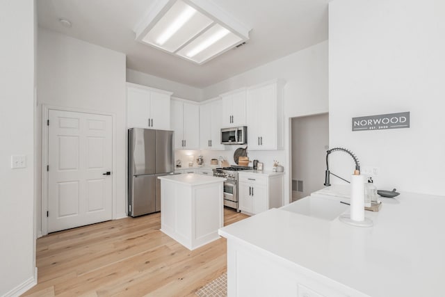 kitchen featuring white cabinetry, sink, a center island, stainless steel appliances, and light hardwood / wood-style floors