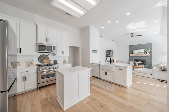 kitchen with ceiling fan, a center island, white cabinetry, and stainless steel appliances