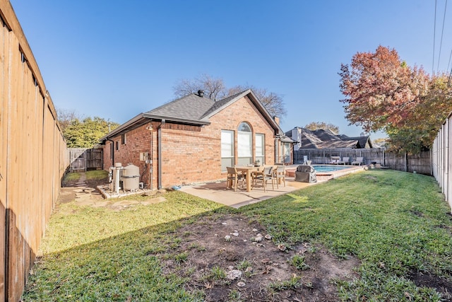 rear view of property featuring a patio area, a fenced in pool, and a yard