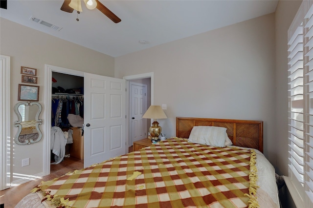 bedroom with multiple windows, a walk in closet, ceiling fan, and a closet