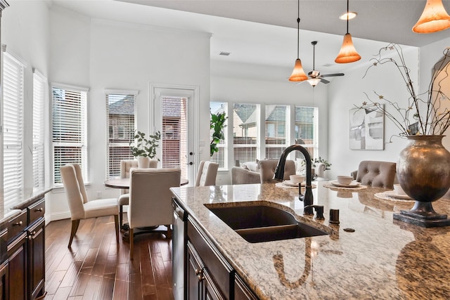 kitchen featuring light stone countertops, decorative light fixtures, sink, plenty of natural light, and dark brown cabinetry