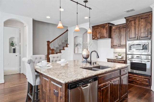 kitchen featuring an island with sink, appliances with stainless steel finishes, pendant lighting, and sink