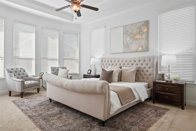 carpeted bedroom featuring crown molding, ceiling fan, and a tray ceiling