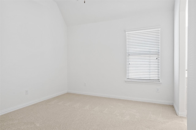 unfurnished room featuring light carpet and vaulted ceiling