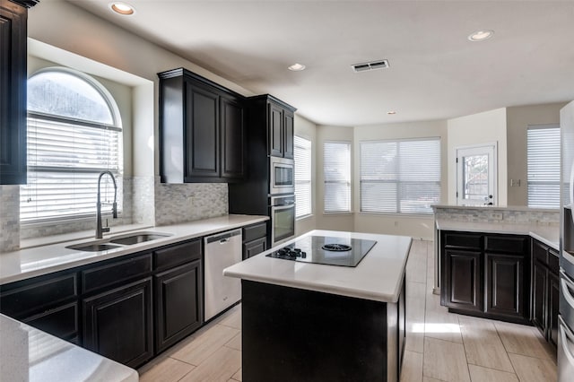 kitchen with backsplash, a kitchen island, sink, and stainless steel appliances