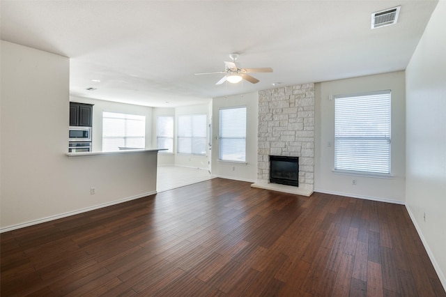 unfurnished living room featuring a fireplace, ceiling fan, and dark wood-type flooring