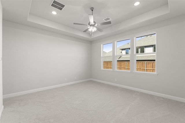 carpeted empty room with a raised ceiling and ceiling fan