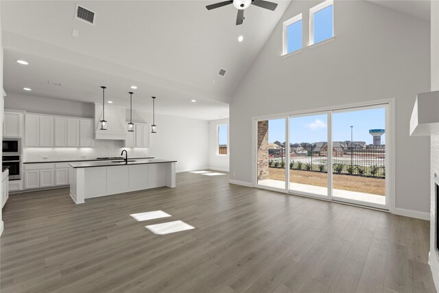 kitchen featuring hanging light fixtures, stainless steel appliances, premium range hood, an island with sink, and gray cabinets