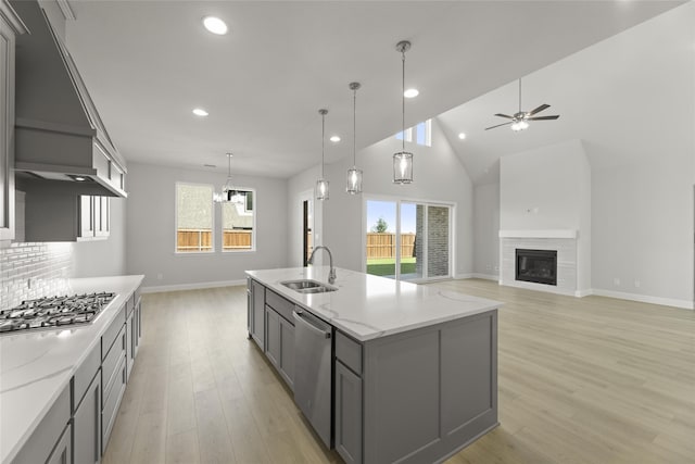 kitchen with light stone countertops, stainless steel appliances, gray cabinets, and sink