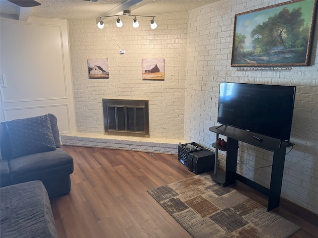 living room featuring hardwood / wood-style floors, a textured ceiling, a brick fireplace, and brick wall