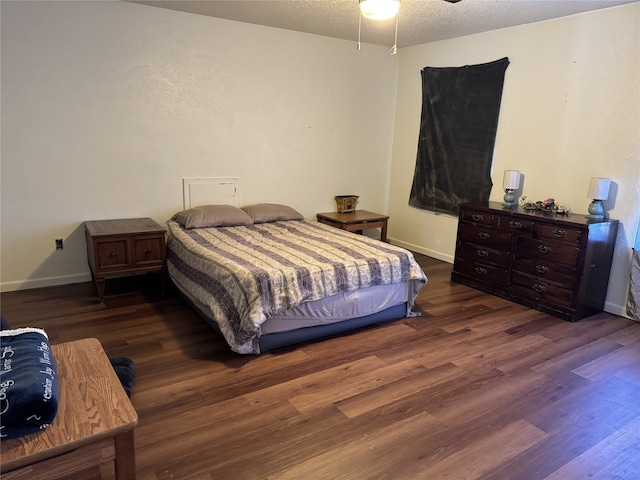 bedroom featuring ceiling fan, dark hardwood / wood-style flooring, and a textured ceiling