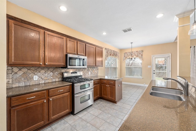 kitchen featuring sink, appliances with stainless steel finishes, hanging light fixtures, tasteful backsplash, and light tile patterned flooring