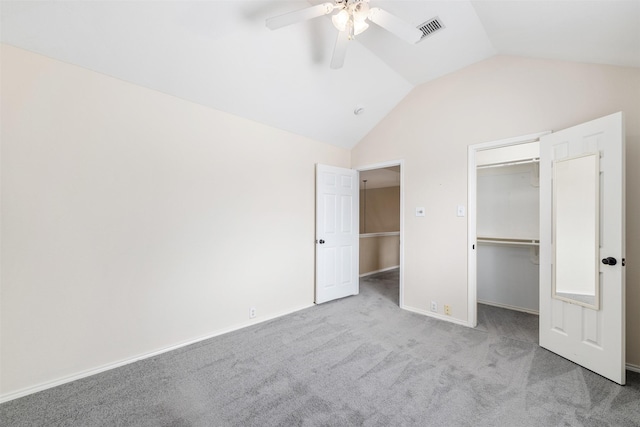 unfurnished bedroom with lofted ceiling, a spacious closet, light colored carpet, a closet, and ceiling fan