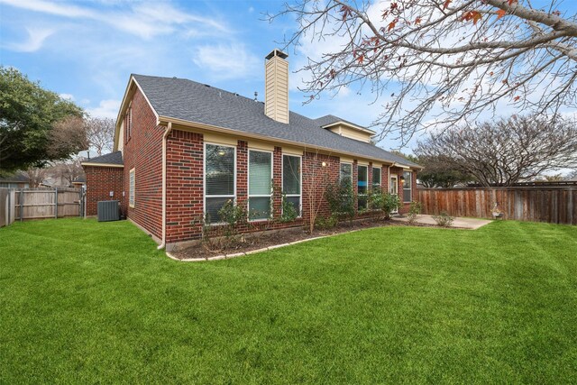 rear view of property with central AC and a yard