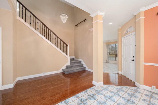 entrance foyer featuring crown molding, decorative columns, light hardwood / wood-style flooring, and a high ceiling