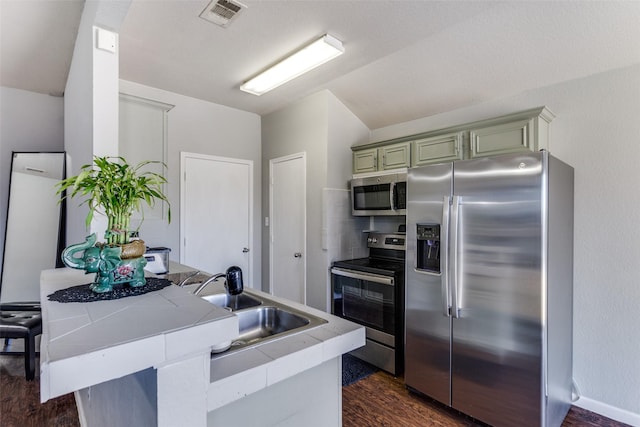 kitchen with kitchen peninsula, sink, appliances with stainless steel finishes, and dark wood-type flooring