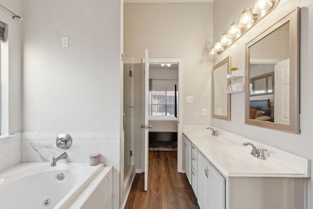 bathroom featuring hardwood / wood-style flooring, a relaxing tiled tub, and vanity