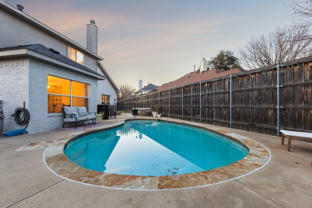 pool at dusk with an outdoor living space and a patio