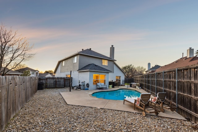 pool at dusk featuring a patio