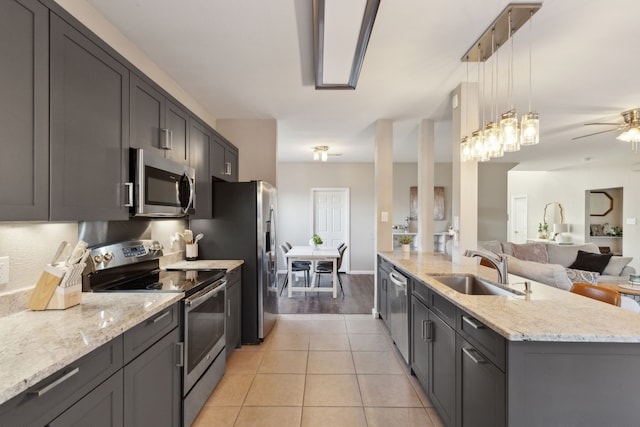 kitchen with sink, hanging light fixtures, a center island with sink, light tile patterned flooring, and appliances with stainless steel finishes