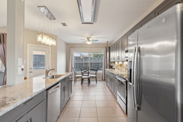 kitchen featuring pendant lighting, sink, ceiling fan, light tile patterned floors, and appliances with stainless steel finishes