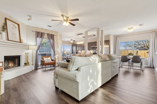 living room with dark hardwood / wood-style flooring, ceiling fan, and a fireplace