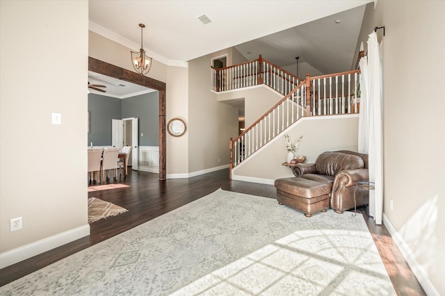 entryway featuring ceiling fan with notable chandelier, dark hardwood / wood-style flooring, and ornamental molding