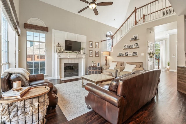 living room featuring a tile fireplace, a high ceiling, and dark hardwood / wood-style floors