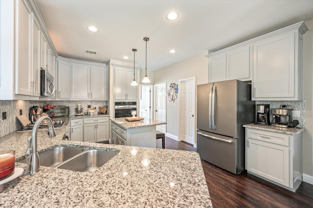 kitchen with white cabinets, a center island, light stone counters, and appliances with stainless steel finishes