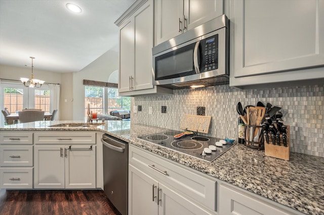 kitchen with an inviting chandelier, sink, appliances with stainless steel finishes, tasteful backsplash, and kitchen peninsula