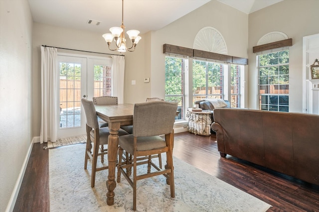 dining room with a wealth of natural light, dark hardwood / wood-style flooring, vaulted ceiling, and a notable chandelier