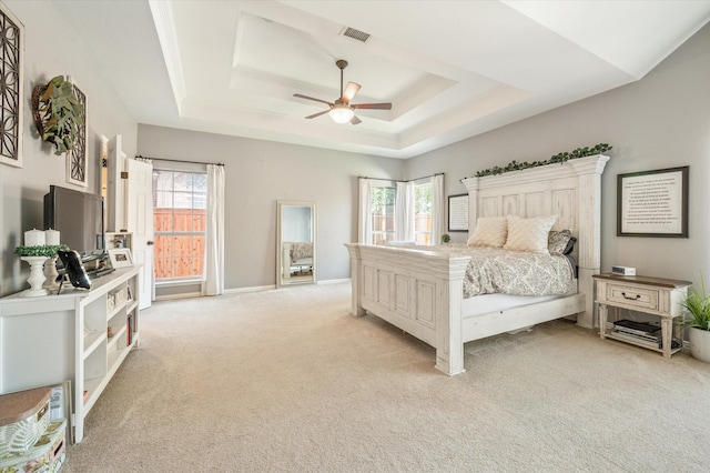 carpeted bedroom featuring a tray ceiling and ceiling fan