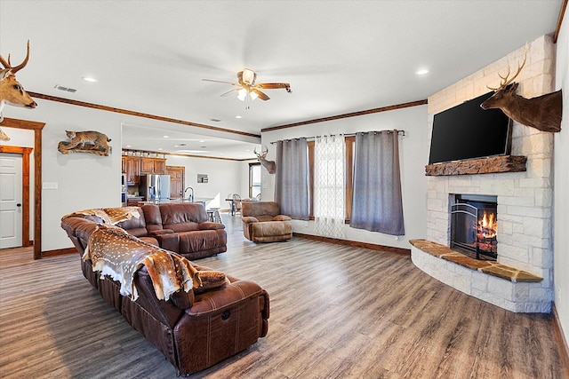 living room featuring a fireplace, hardwood / wood-style floors, ceiling fan, and ornamental molding